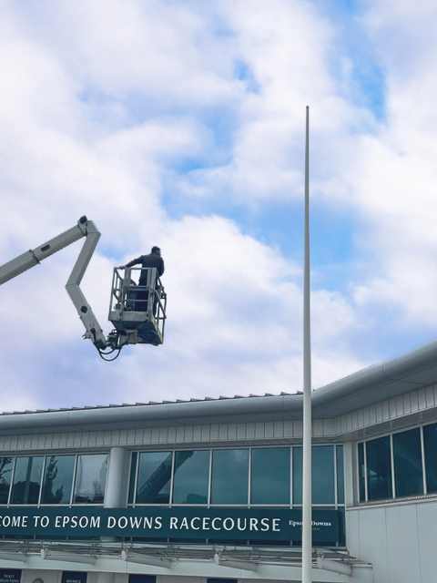 A man is working on a flagpole in front of a building.	