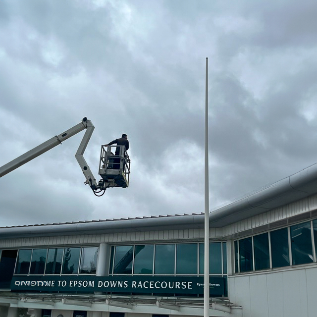 A man is working on a flagpole in front of a building.